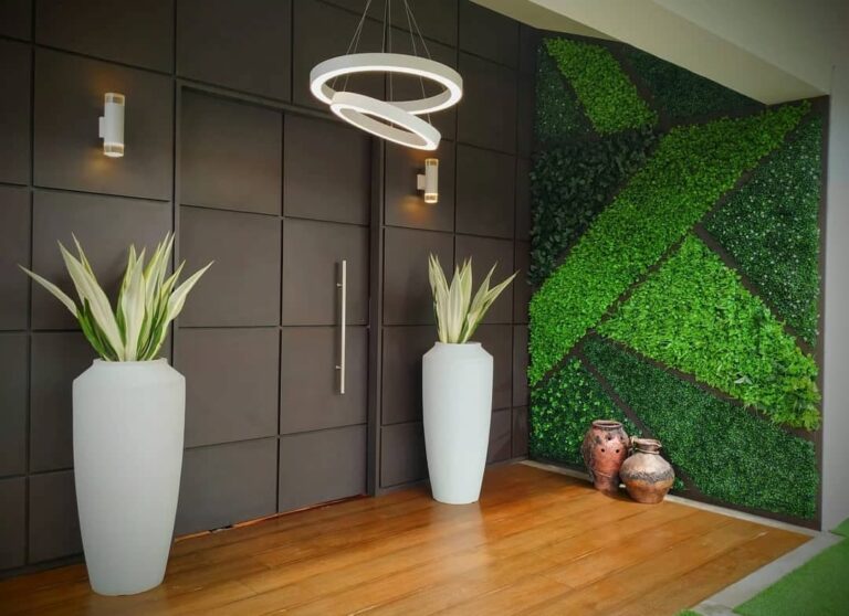 Jardín vertical geométrico en la entrada de una vivienda, con maceteros de fibra y suelo de madera