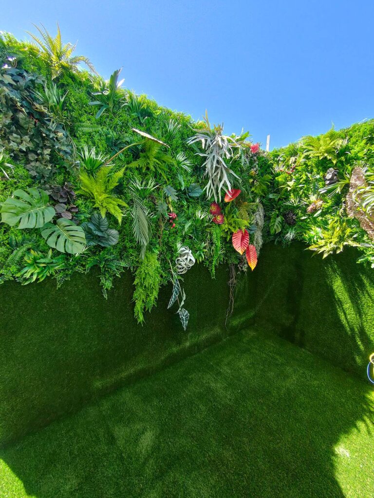 Muro verde exterior visto desde abajo, con césped artificial en el suelo