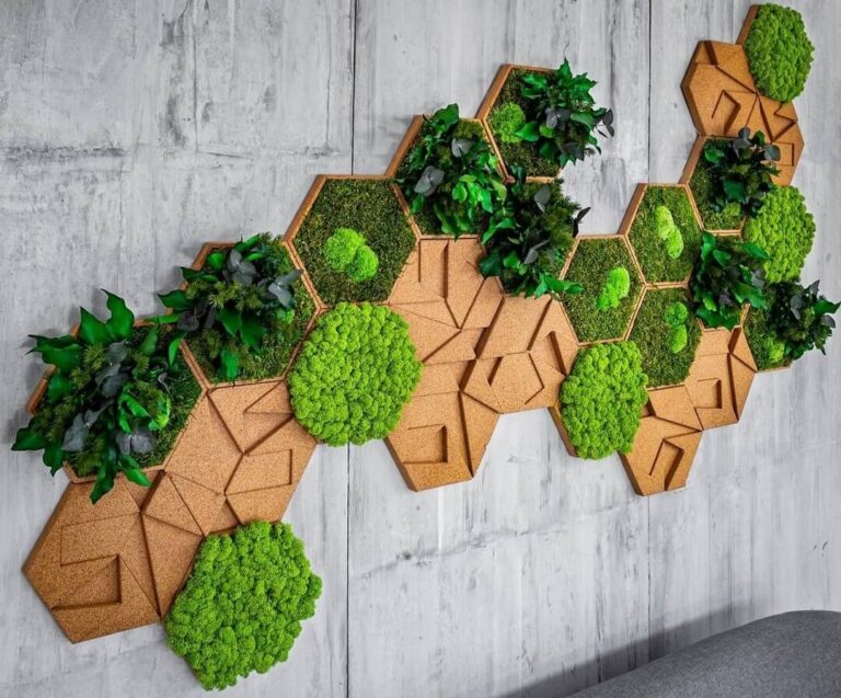 Panel hexagonal de musgo preservado y plantas artificiales sobre pared de hormigón