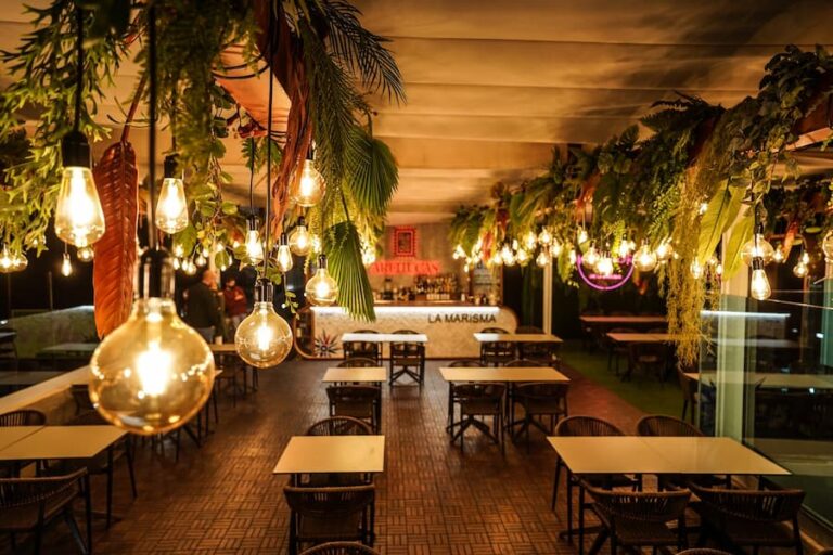 Restaurante con jardín vertical y plantas colgantes iluminadas con bombillas decorativas